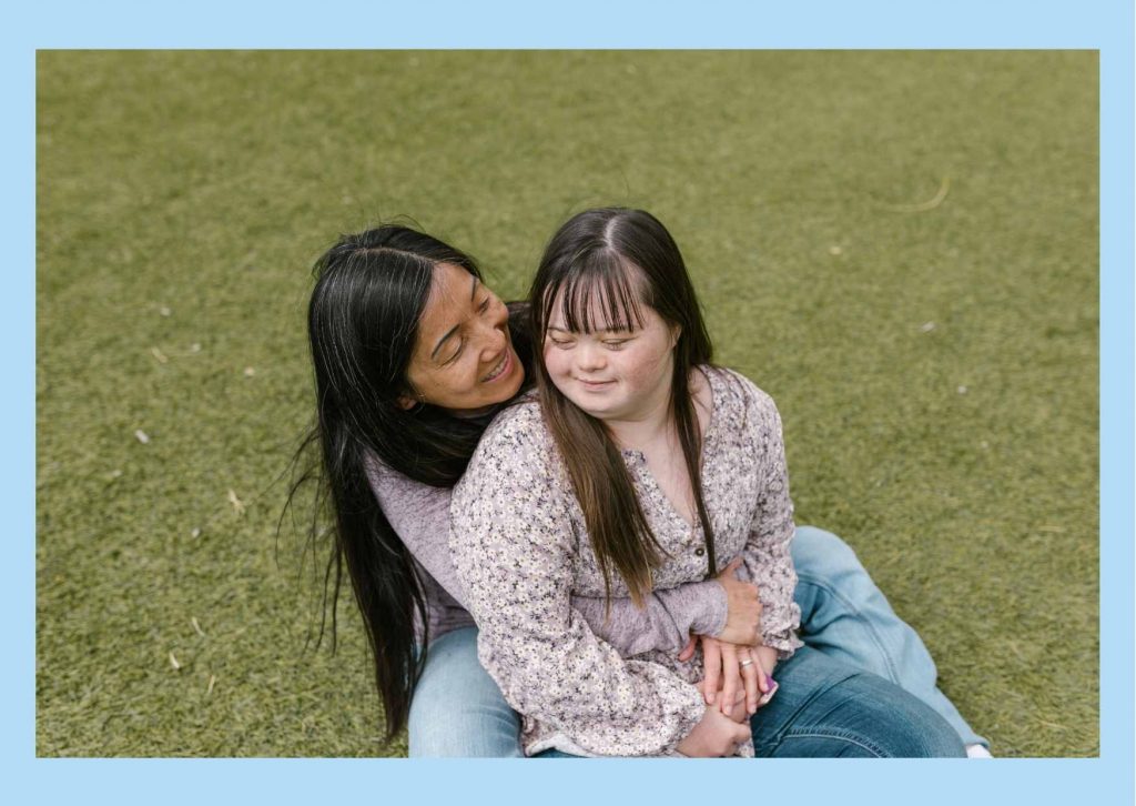 Mother and daughter with Downs syndrome cuddling and smiling