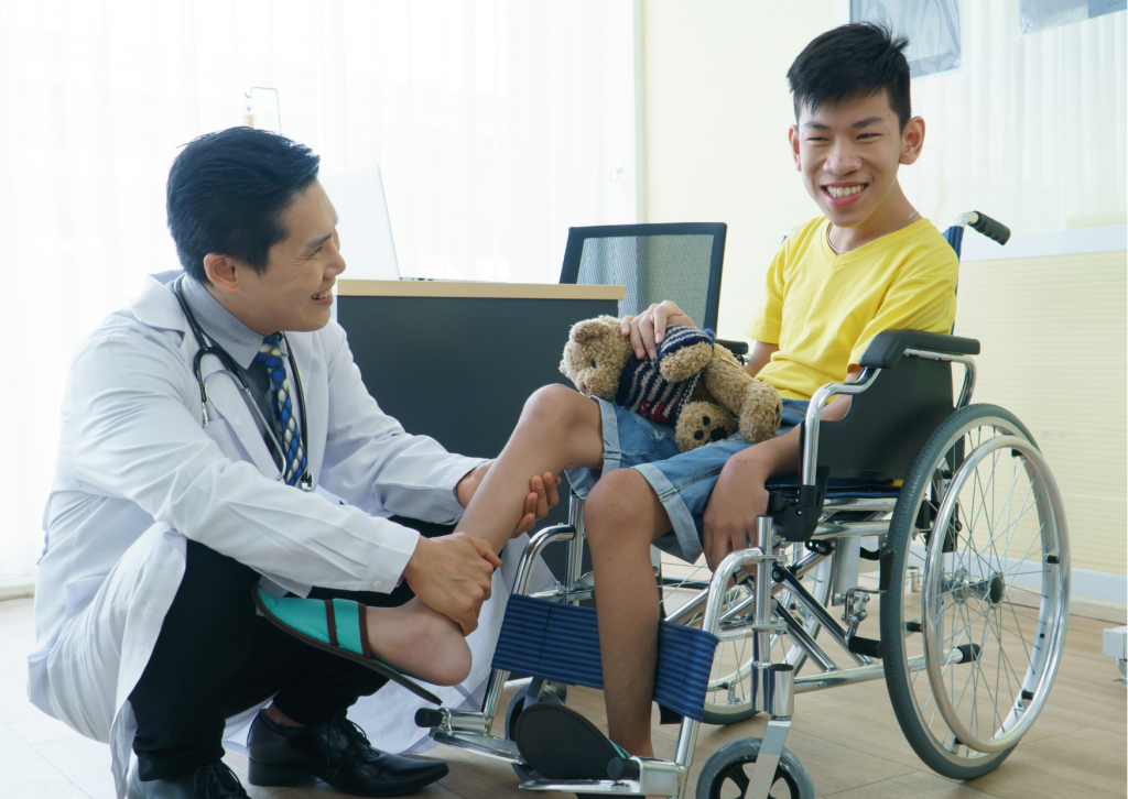 Asian male doctor assists young Asian male wheelchair user