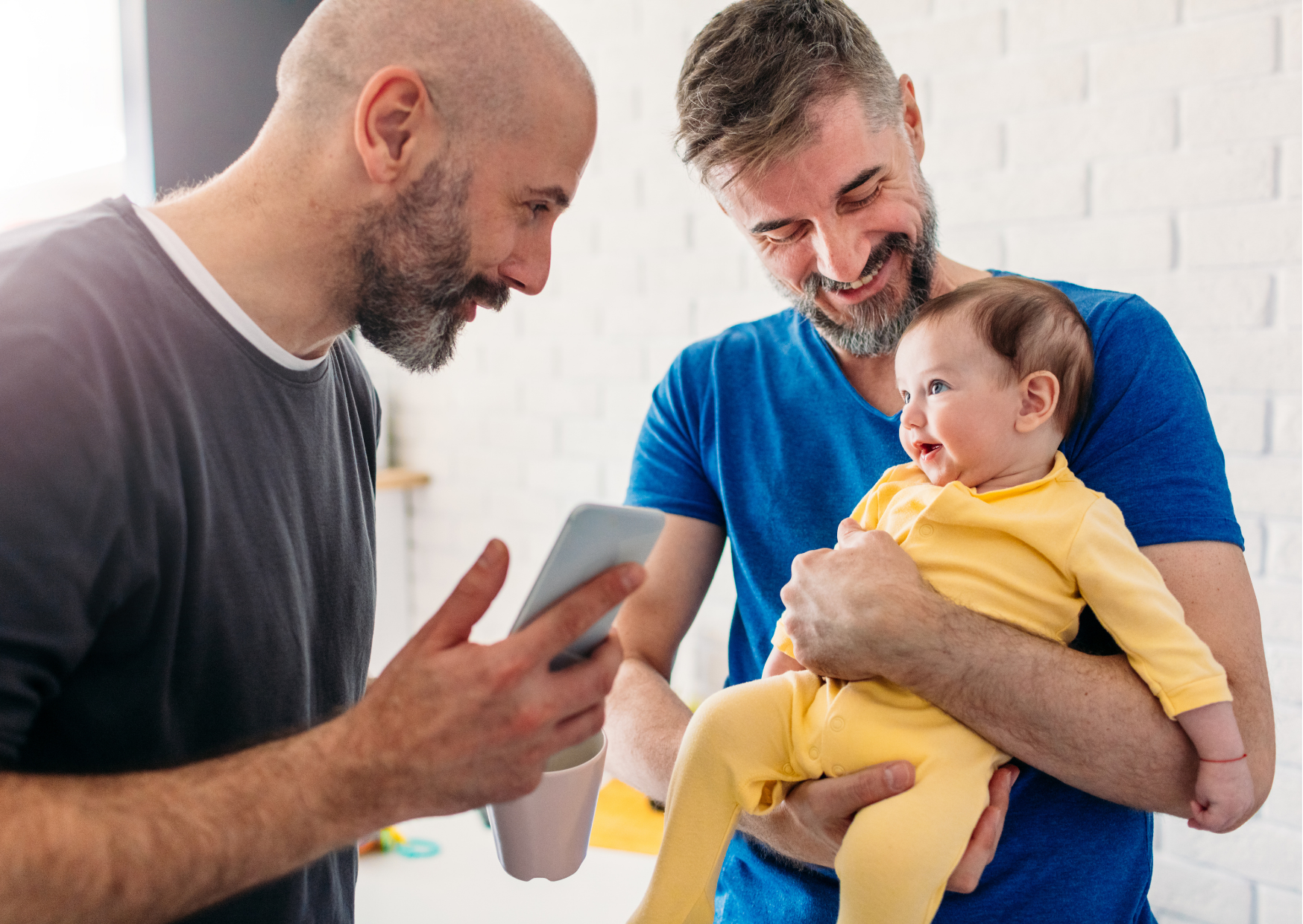 Two smiling men with a smiling baby.