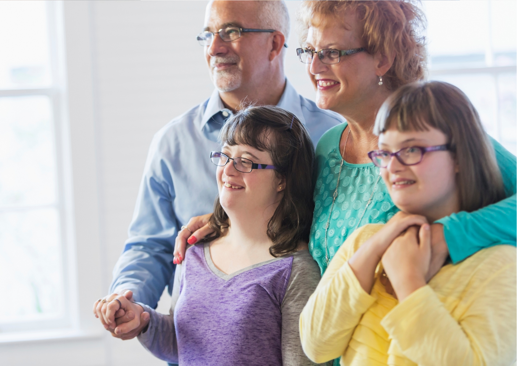 two smiling older adults with two smiling teen girls.