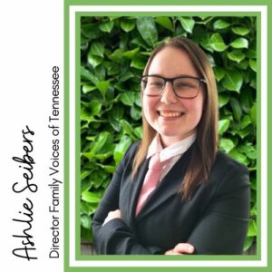Headshot of Ashlie Seibers, Director of Family Voices of Tennessee. Ashlie is white woman with long brown hair. She is wearing a black suit jacket, a white shirt, and a pink tie. The background is green leaves.